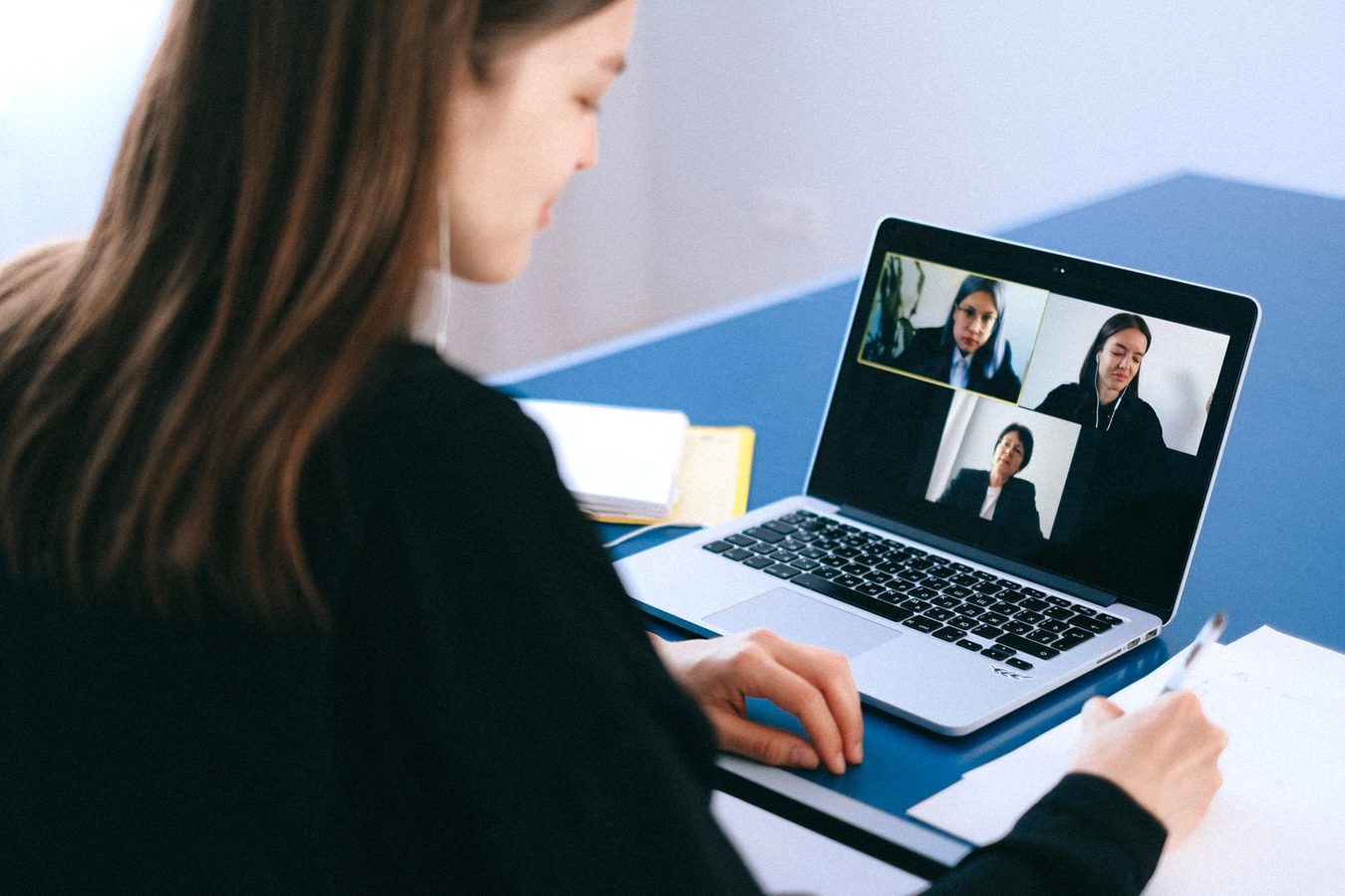 A laptop on a desk showing a video call with several participants