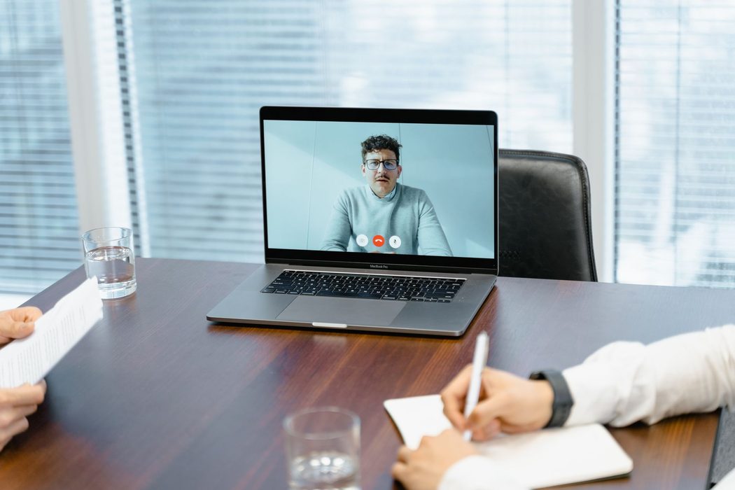 A laptop on a desk showing a video call with several participants on screen